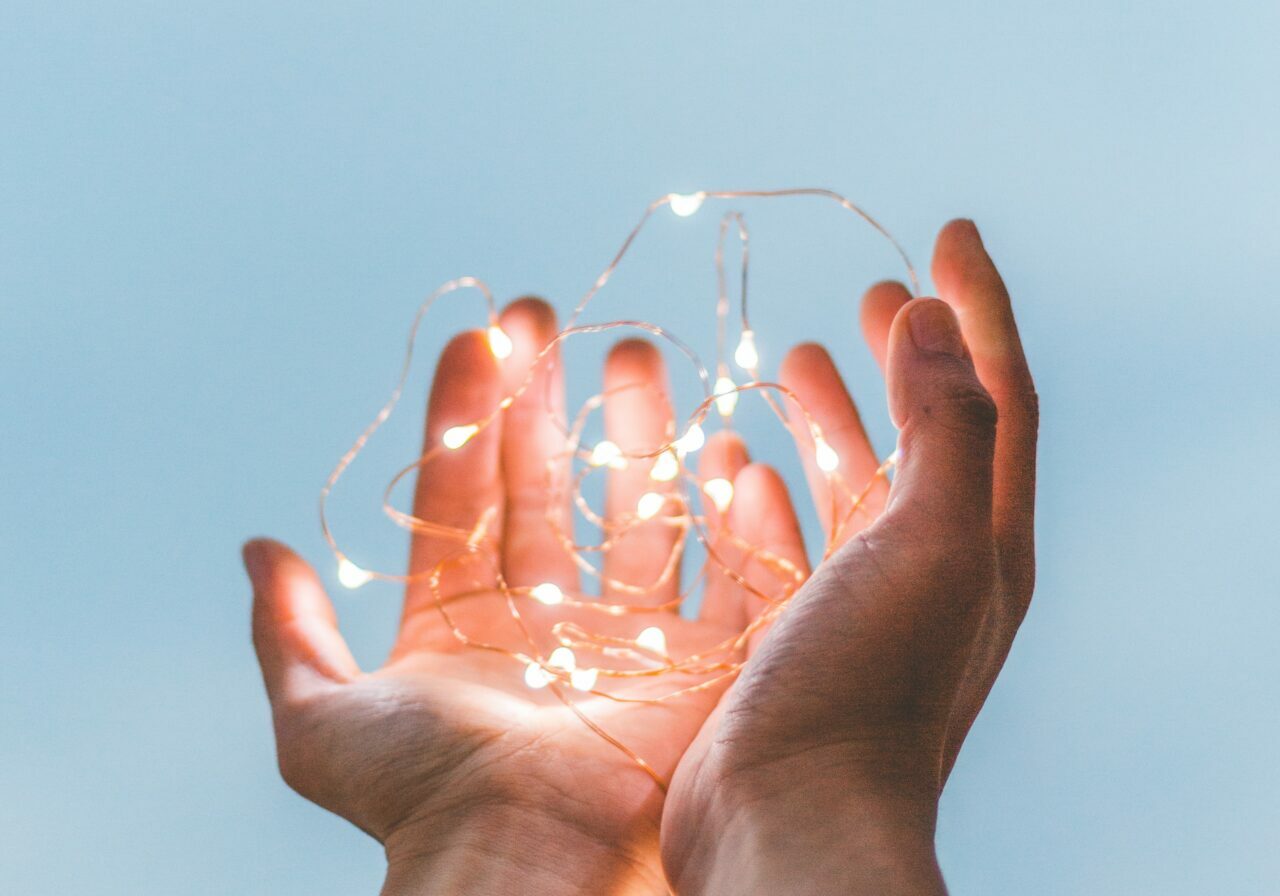 A pair of hands holding string lights.